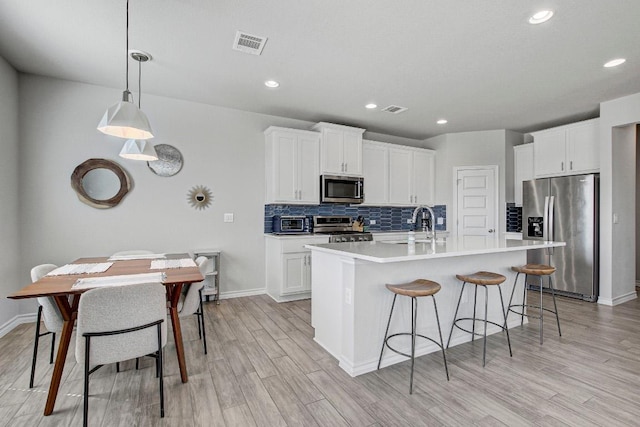 kitchen featuring light wood finished floors, visible vents, appliances with stainless steel finishes, and tasteful backsplash