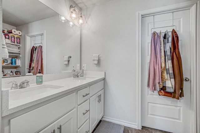 bathroom with a sink, baseboards, and double vanity