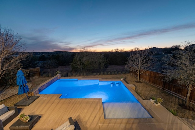 pool at dusk featuring a fenced in pool and a fenced backyard