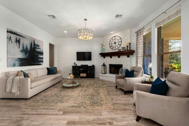 living area with visible vents, a fireplace, and wood finished floors