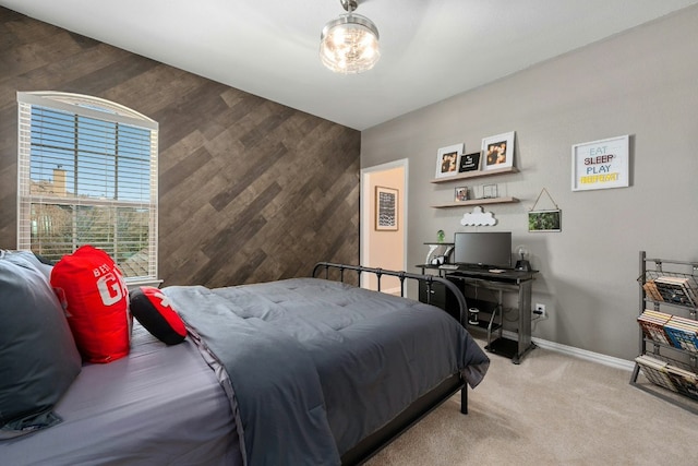 carpeted bedroom featuring an accent wall, wooden walls, and baseboards