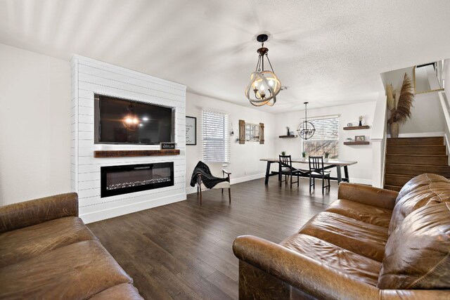 living room featuring a large fireplace, a notable chandelier, stairway, and wood finished floors