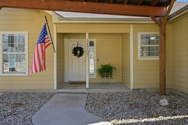 entrance to property with a shingled roof and covered porch