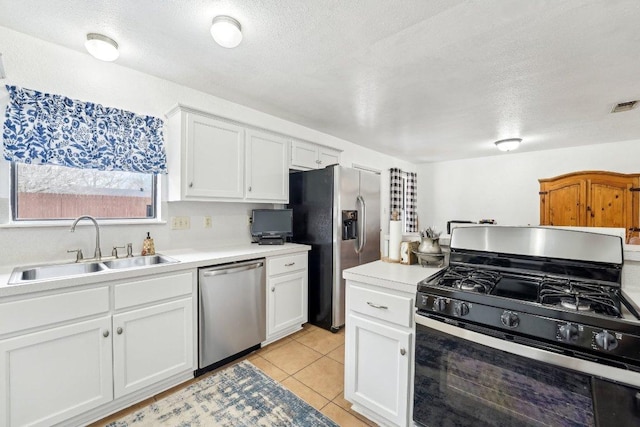 402 Laurel St, Bastrop, TX 78602 - kitchen with stainless steel appliances, white cabinets, light countertops, a textured ceiling, and light tile patterned flooring