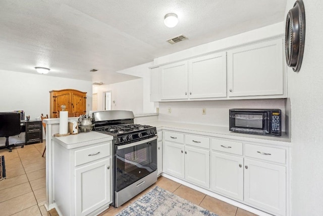 402 Laurel St, Bastrop, TX 78602 - kitchen featuring stainless steel gas range oven, light tile patterned floors, a peninsula, light countertops, and a textured ceiling