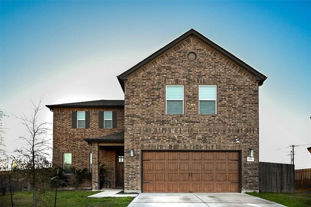 view of front of property with driveway, brick siding, an attached garage, and fence