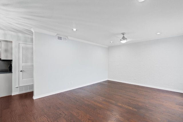 unfurnished room with ceiling fan, brick wall, wood finished floors, and visible vents