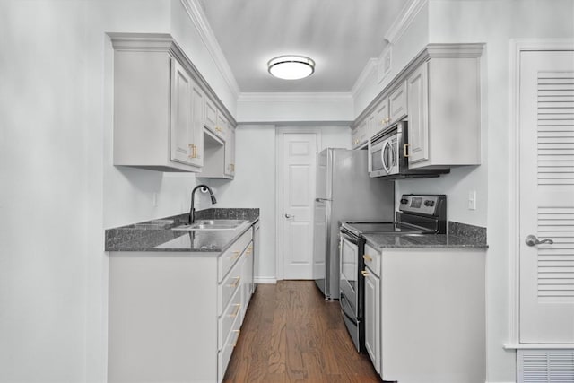 kitchen with appliances with stainless steel finishes, dark stone countertops, dark wood-type flooring, crown molding, and a sink