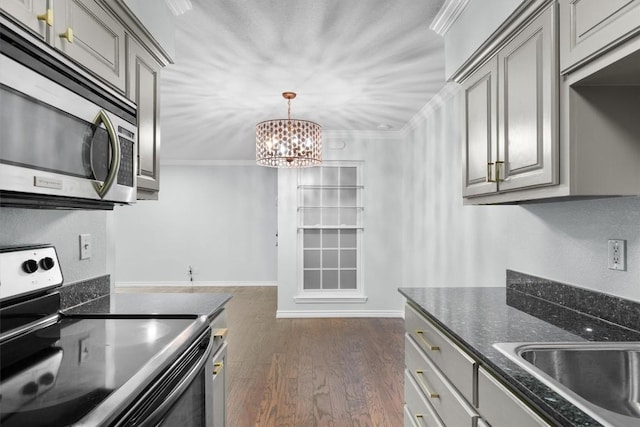 kitchen with baseboards, ornamental molding, appliances with stainless steel finishes, gray cabinets, and dark wood finished floors