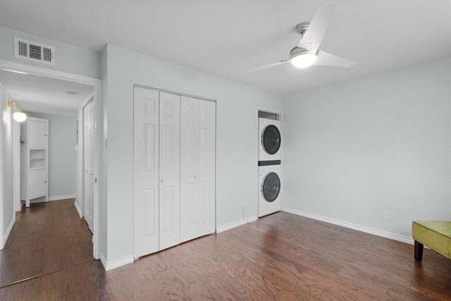 unfurnished bedroom featuring a closet, visible vents, wood finished floors, and stacked washer and clothes dryer