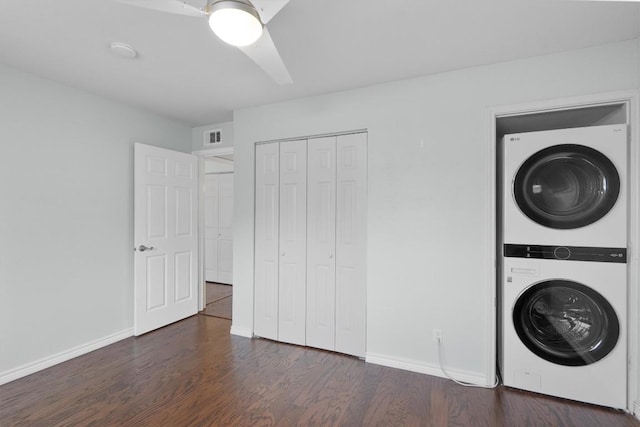 washroom with laundry area, baseboards, visible vents, stacked washer and clothes dryer, and wood finished floors