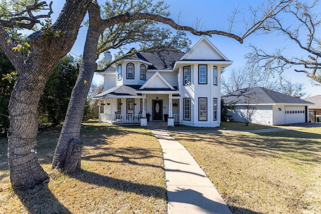 victorian home featuring roof with shingles, a chimney, a porch, a garage, and a front lawn