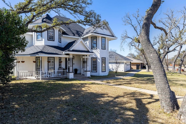 victorian house with a shingled roof, covered porch, and a front lawn