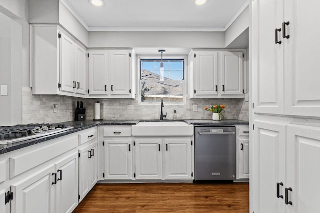 kitchen with dark countertops, white cabinetry, stainless steel appliances, and a sink