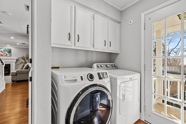 laundry area with cabinet space, wood finished floors, crown molding, a fireplace, and separate washer and dryer