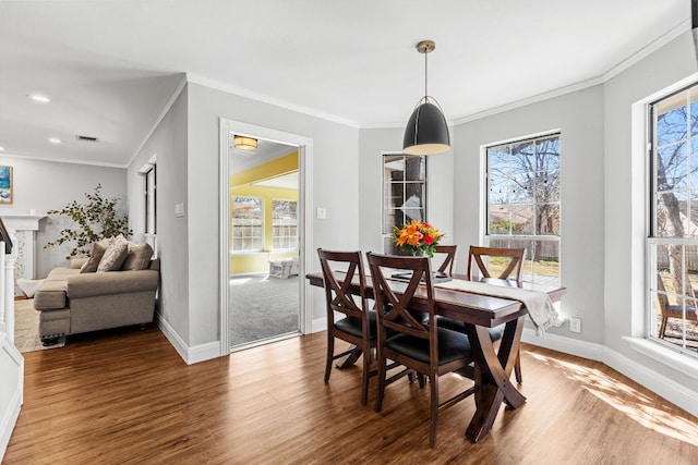 dining room with visible vents, a fireplace, baseboards, and wood finished floors