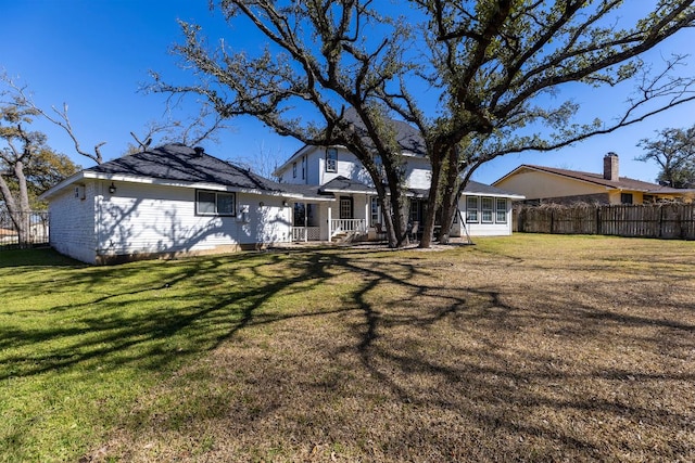 back of property with fence and a lawn