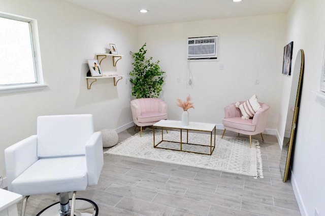 living area featuring baseboards, a wall unit AC, and recessed lighting