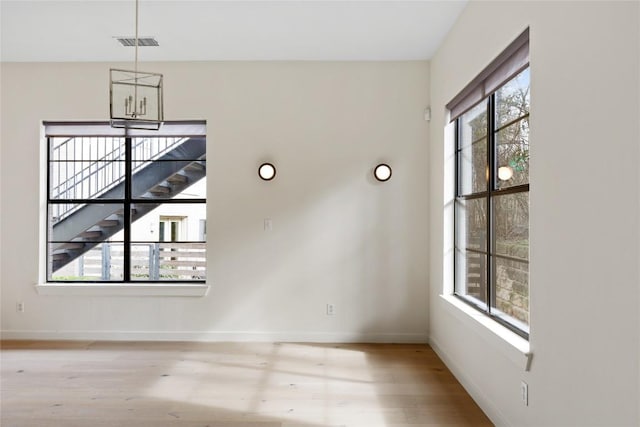 unfurnished dining area featuring visible vents, an inviting chandelier, light wood-style flooring, and baseboards