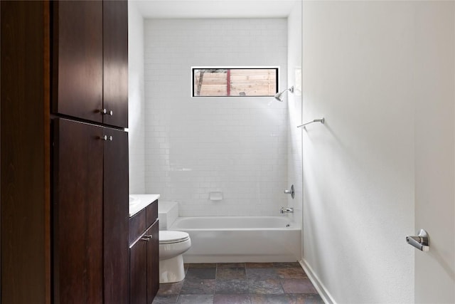 full bath featuring baseboards, bathing tub / shower combination, toilet, stone finish flooring, and vanity