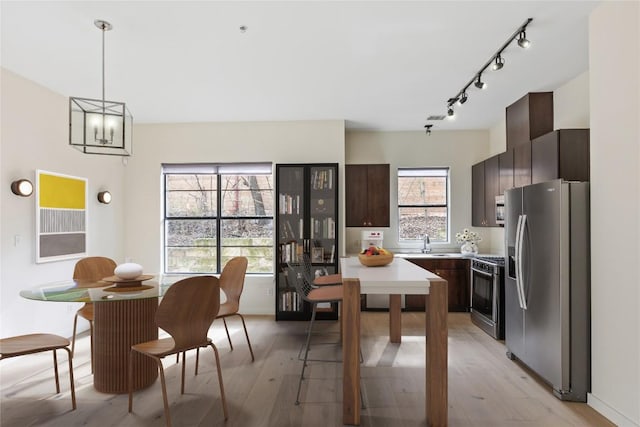 kitchen featuring a sink, light countertops, appliances with stainless steel finishes, dark brown cabinets, and light wood-type flooring