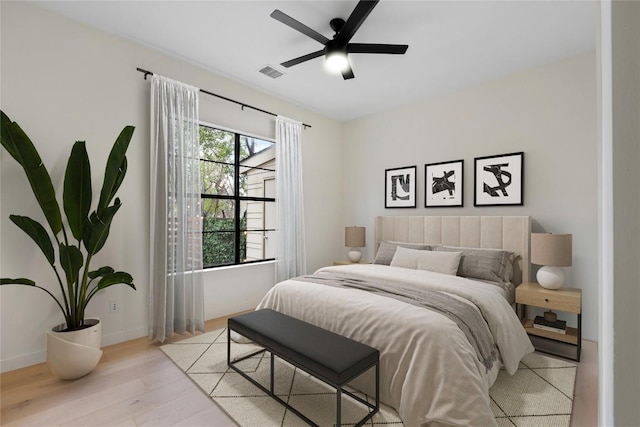 bedroom featuring light wood finished floors, baseboards, visible vents, and ceiling fan