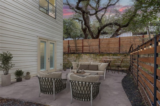 patio terrace at dusk with french doors, a fenced backyard, and an outdoor hangout area