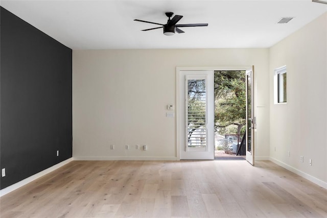 empty room featuring light wood-type flooring, baseboards, visible vents, and a ceiling fan