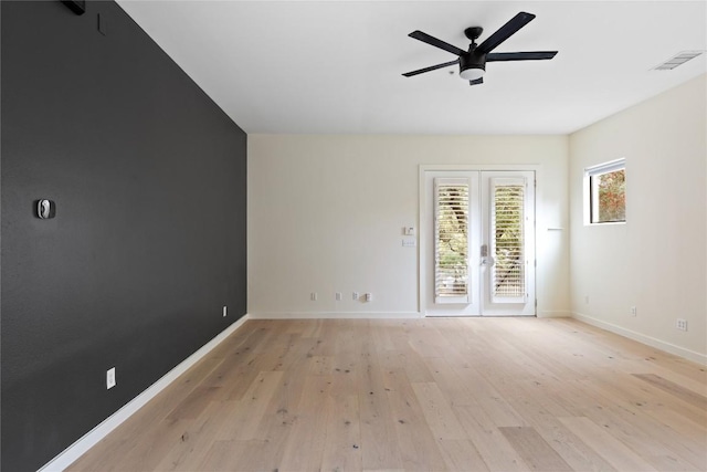 spare room featuring light wood finished floors, baseboards, visible vents, and a ceiling fan