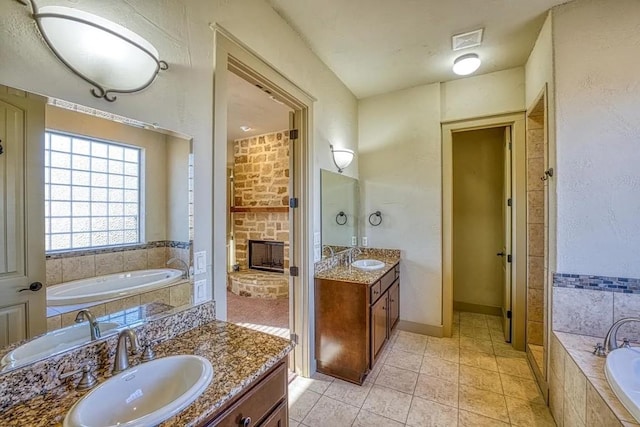 102 Maravilla Way, Horseshoe Bay, TX 78657 - bathroom featuring two vanities, a bath, tile patterned flooring, and a fireplace