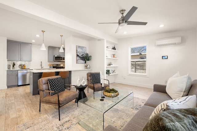 living room featuring recessed lighting, baseboards, light wood finished floors, and a wall mounted AC