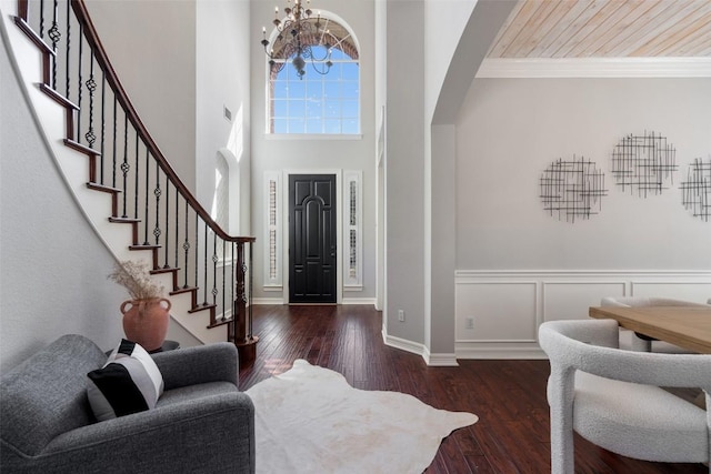 entryway with a chandelier, arched walkways, hardwood / wood-style floors, and stairs