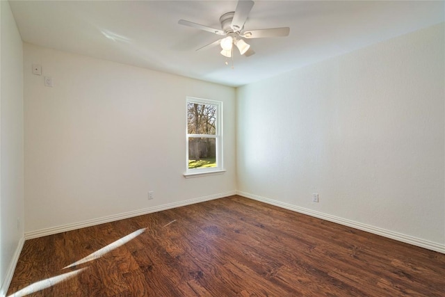 spare room featuring a ceiling fan, dark wood-style flooring, and baseboards