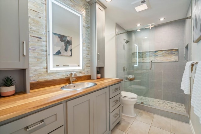 bathroom featuring toilet, a stall shower, vanity, and tile patterned floors