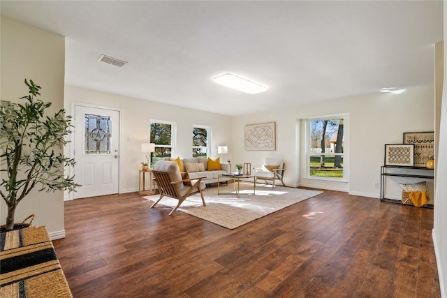 living area featuring dark wood-style flooring, visible vents, and baseboards