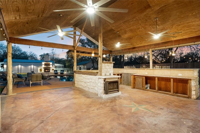 view of patio featuring ceiling fan, fence, exterior kitchen, and a gazebo