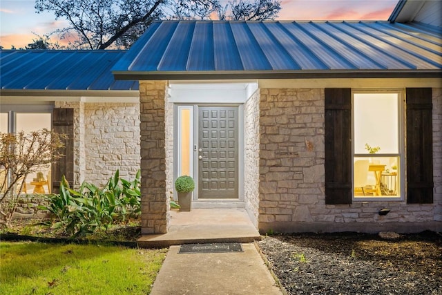 entrance to property featuring stone siding, metal roof, and a standing seam roof