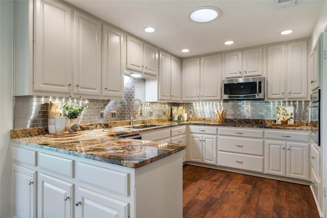 kitchen with dark wood finished floors, stainless steel microwave, a sink, and white cabinetry