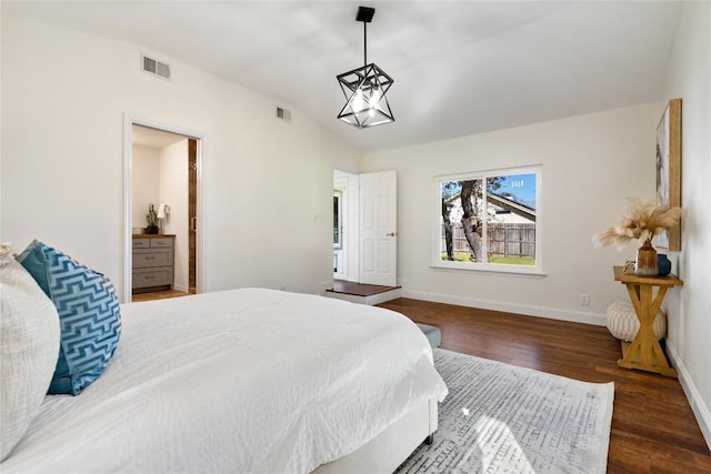 bedroom with visible vents, vaulted ceiling, wood finished floors, a chandelier, and baseboards