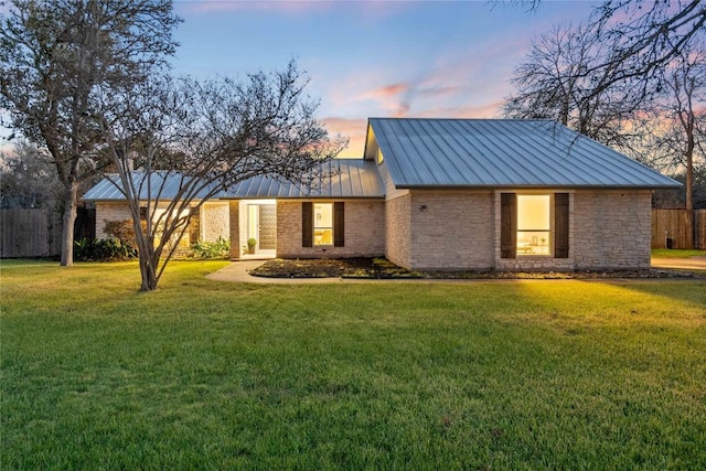 view of front of property featuring a standing seam roof, fence, metal roof, and a front yard