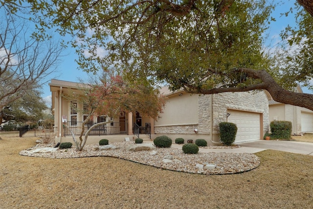 view of front of property with driveway, stone siding, an attached garage, a porch, and stucco siding