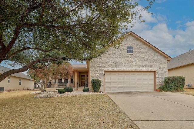 view of front of property with a garage, stone siding, driveway, and a front lawn