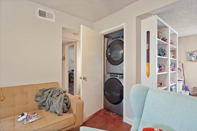 laundry area featuring laundry area, visible vents, a textured ceiling, and stacked washing maching and dryer