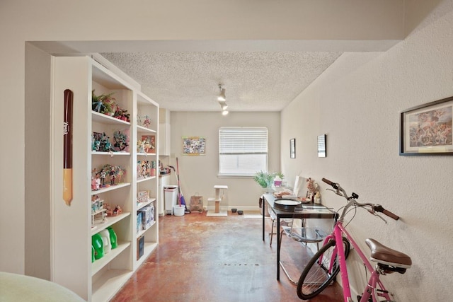 interior space featuring finished concrete floors, a textured ceiling, and a textured wall