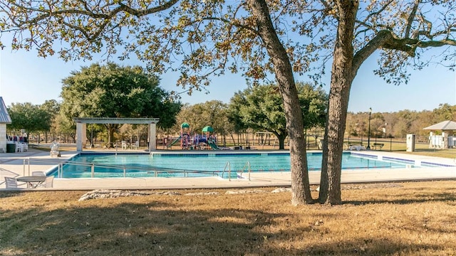 community pool with playground community, fence, and a lawn