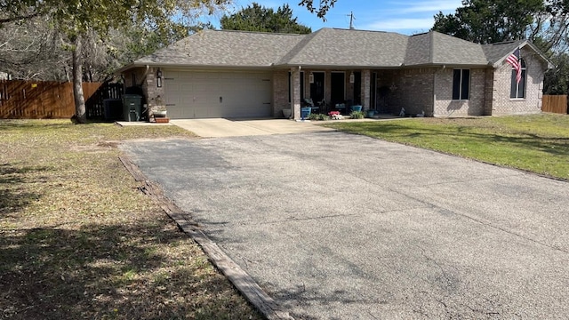 ranch-style house featuring an attached garage, fence, aphalt driveway, and brick siding