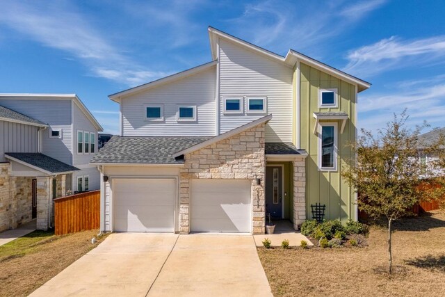 view of front facade featuring roof with shingles, concrete driveway, board and batten siding, a garage, and stone siding