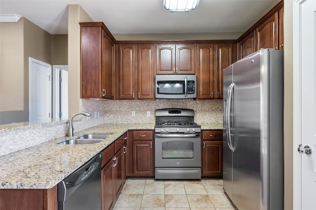 kitchen with light stone countertops, decorative backsplash, stainless steel appliances, and a sink