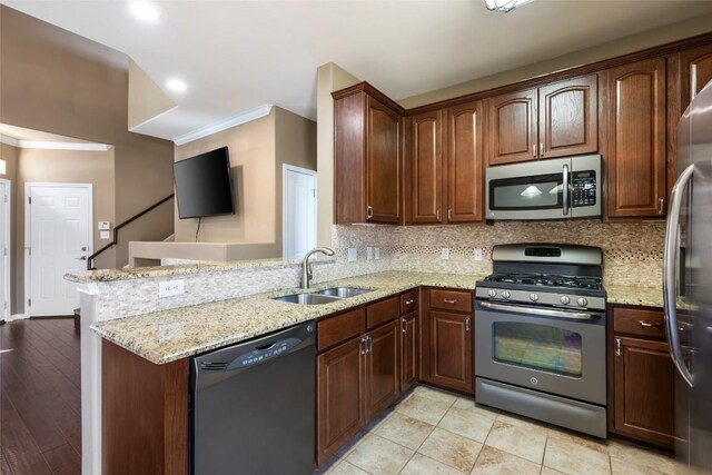 kitchen with stainless steel appliances, tasteful backsplash, ornamental molding, a sink, and a peninsula