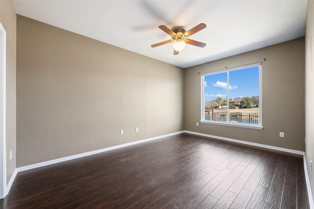 unfurnished room with dark wood-style floors, ceiling fan, and baseboards